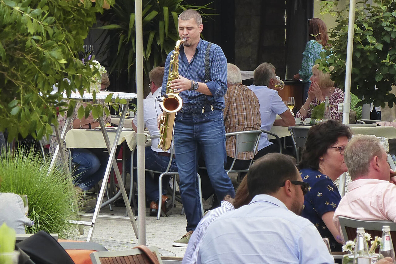 Live-Musik mit Saxophonist auf einer DIVINO-Veranstaltung im Freien, Gäste sitzen an Tischen.